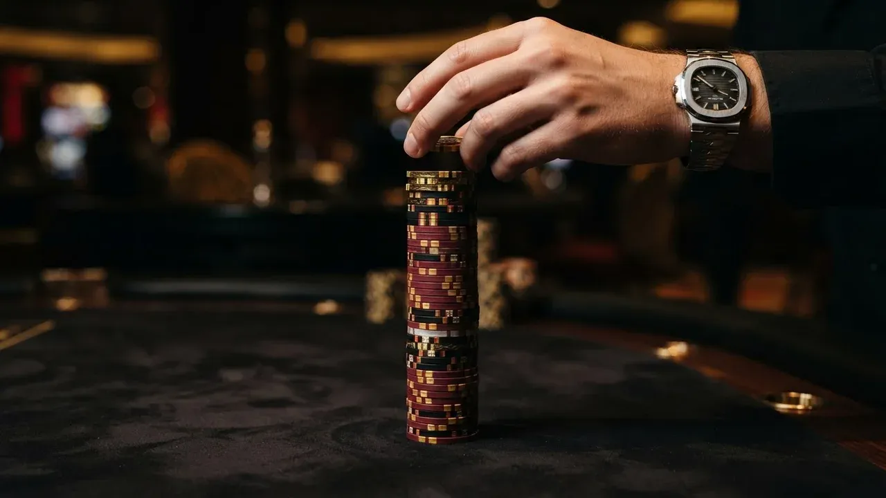 Mano colocando una pila de fichas de casino sobre una mesa oscura